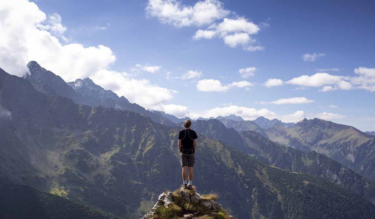 Man står på toppen av ett berg och ser ut över en soldränkt dal.