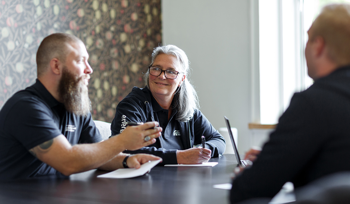 Tre ingenjörer från Energikontoret i Mälardalen diskuterar energieffektivt näringsliv runt ett mörkt träbord i en ljus konferenslokal.